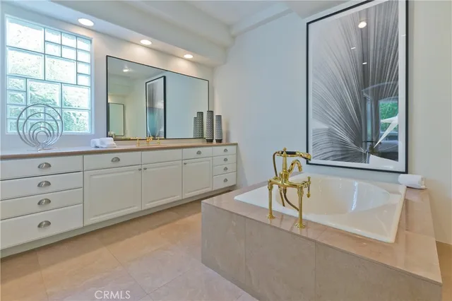 a bathroom with a tub a sink and a large mirror next to a window