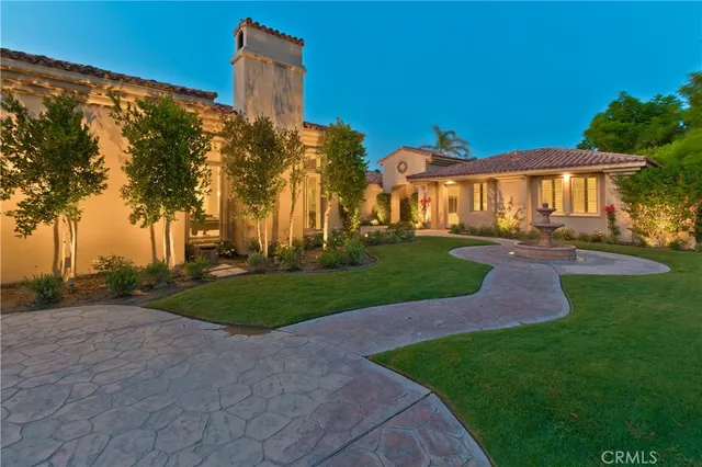 a view of a white house next to a yard with big trees