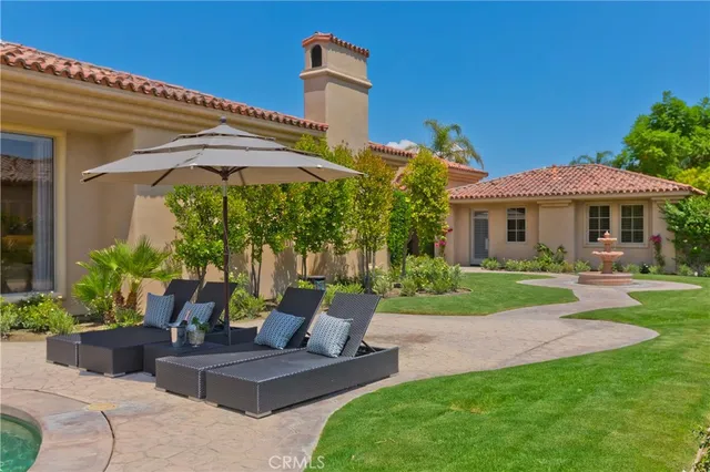 a view of a patio with couches table and chairs under an umbrella
