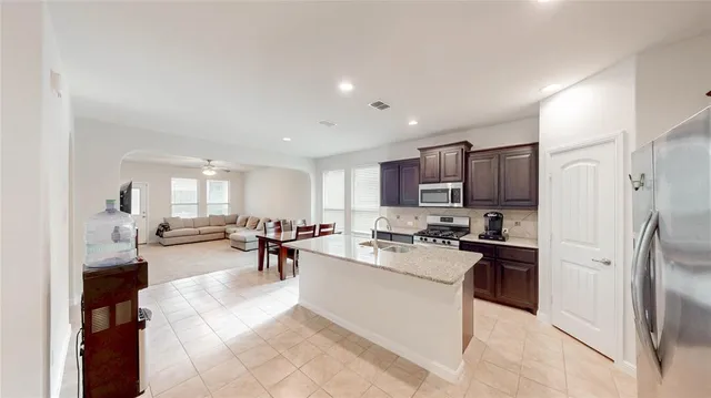 a kitchen with stainless steel appliances kitchen island granite countertop a refrigerator and cabinets