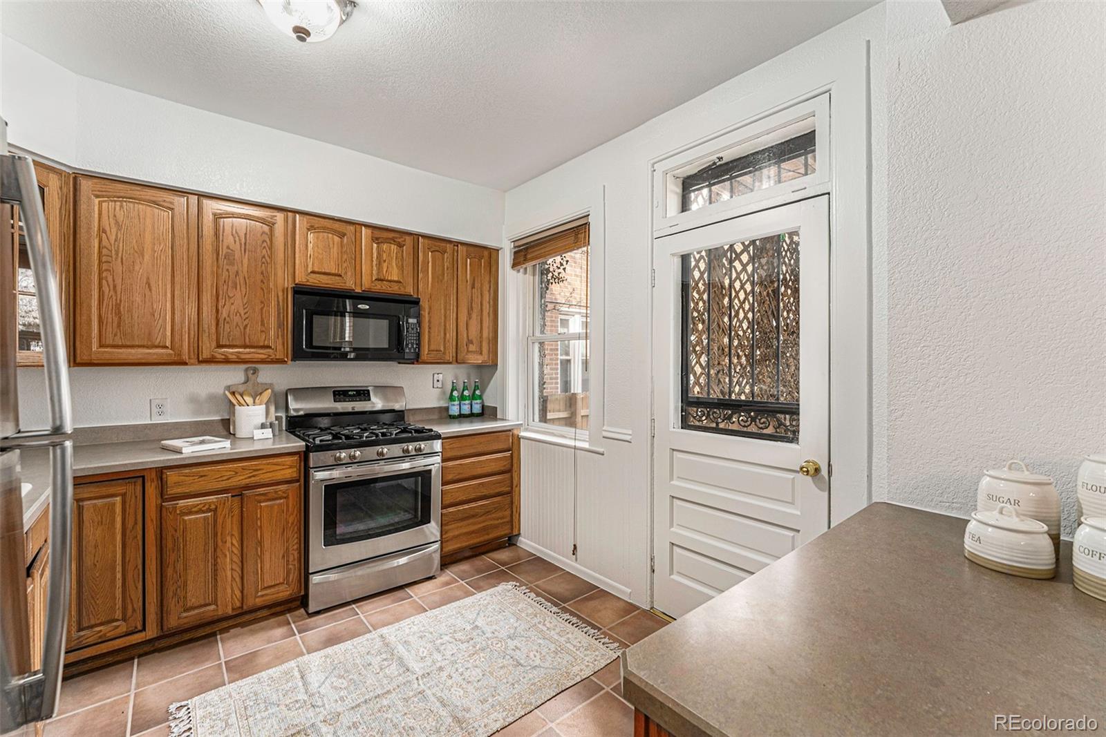 1314 Vine Street Denver, CO 80206 - Photo 11 of 34 a kitchen with stainless steel appliances granite countertop a stove top oven a sink and a microwave