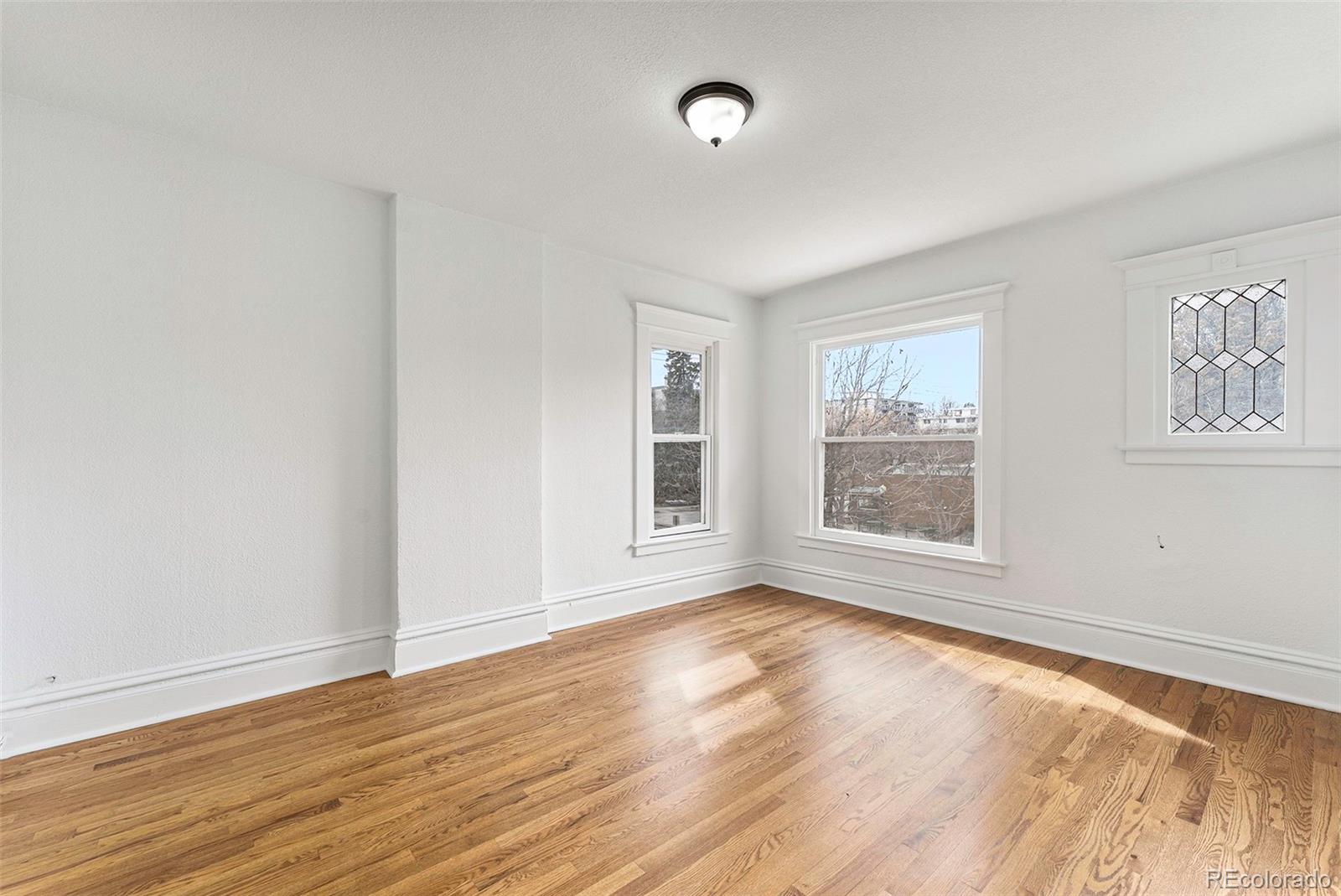 1314 Vine Street Denver, CO 80206 - Photo 19 of 34 a view of an empty room with wooden floor and a window