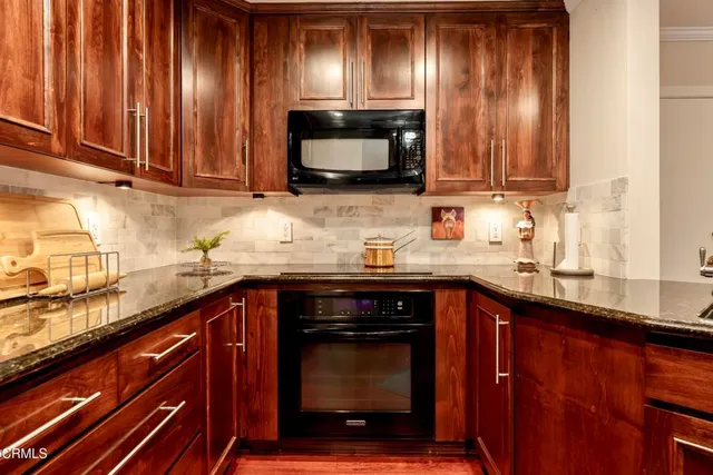 a kitchen with granite countertop wood cabinets stainless steel appliances and a sink