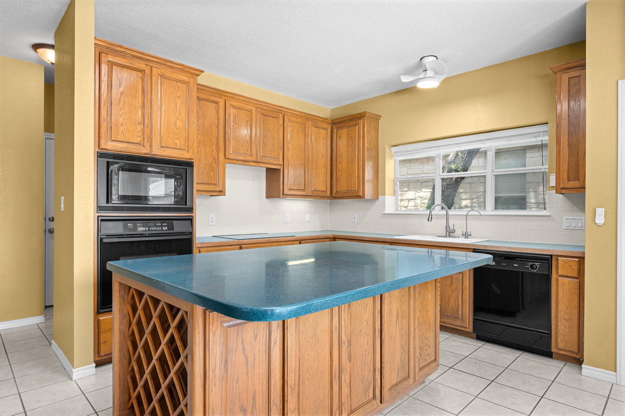 108 Thornwood Road Georgetown, TX 78628 - Photo 13 of 40 A classic kitchen showcases honey-toned cabinetry, an integrated wine rack, and a striking teal island countertop.