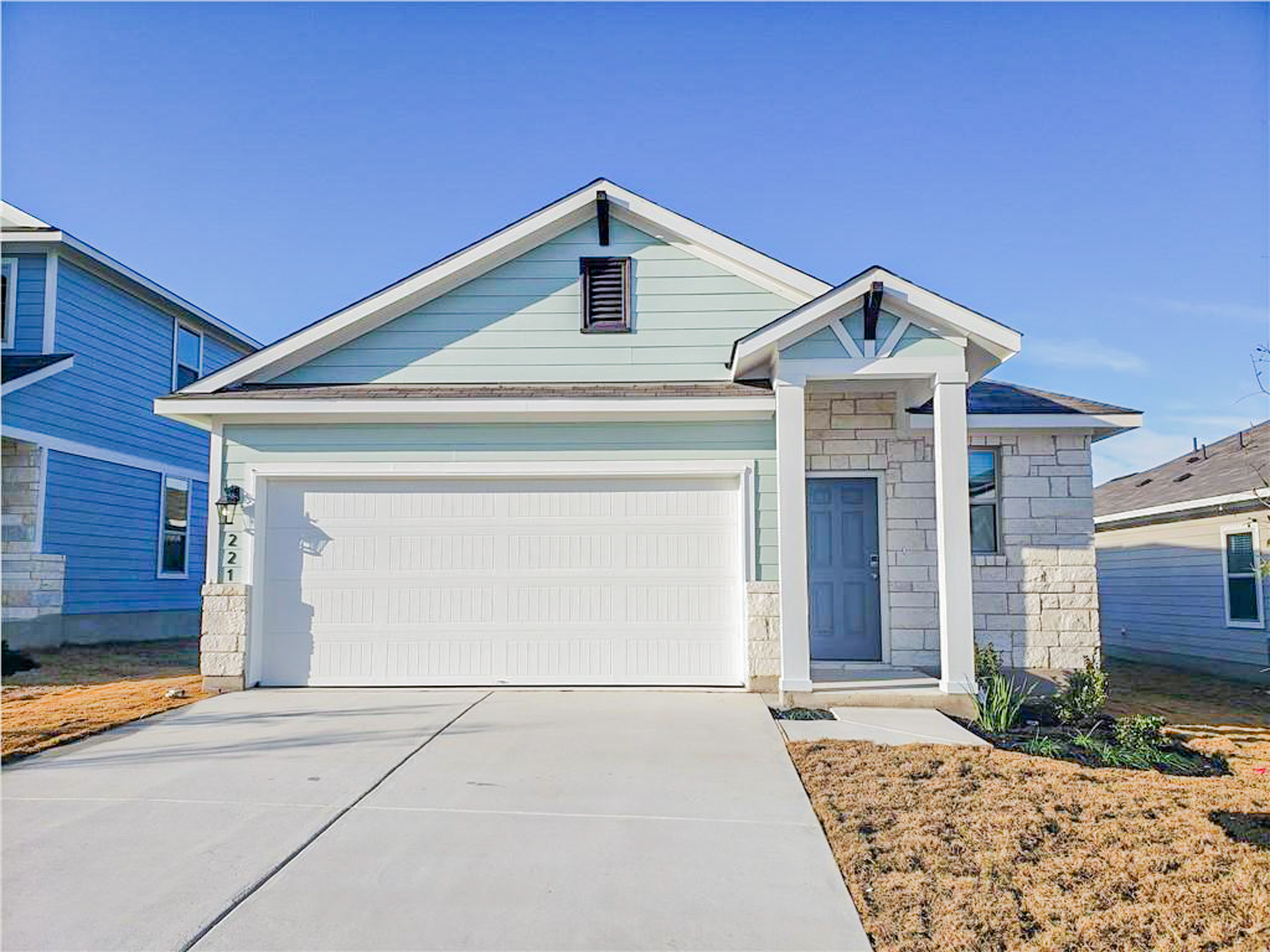 View of front facade featuring driveway, an attached garage, and stone siding