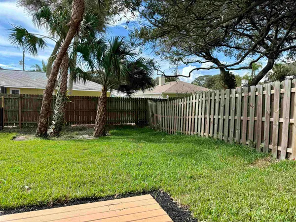 a view of backyard with wooden fence and a large tree