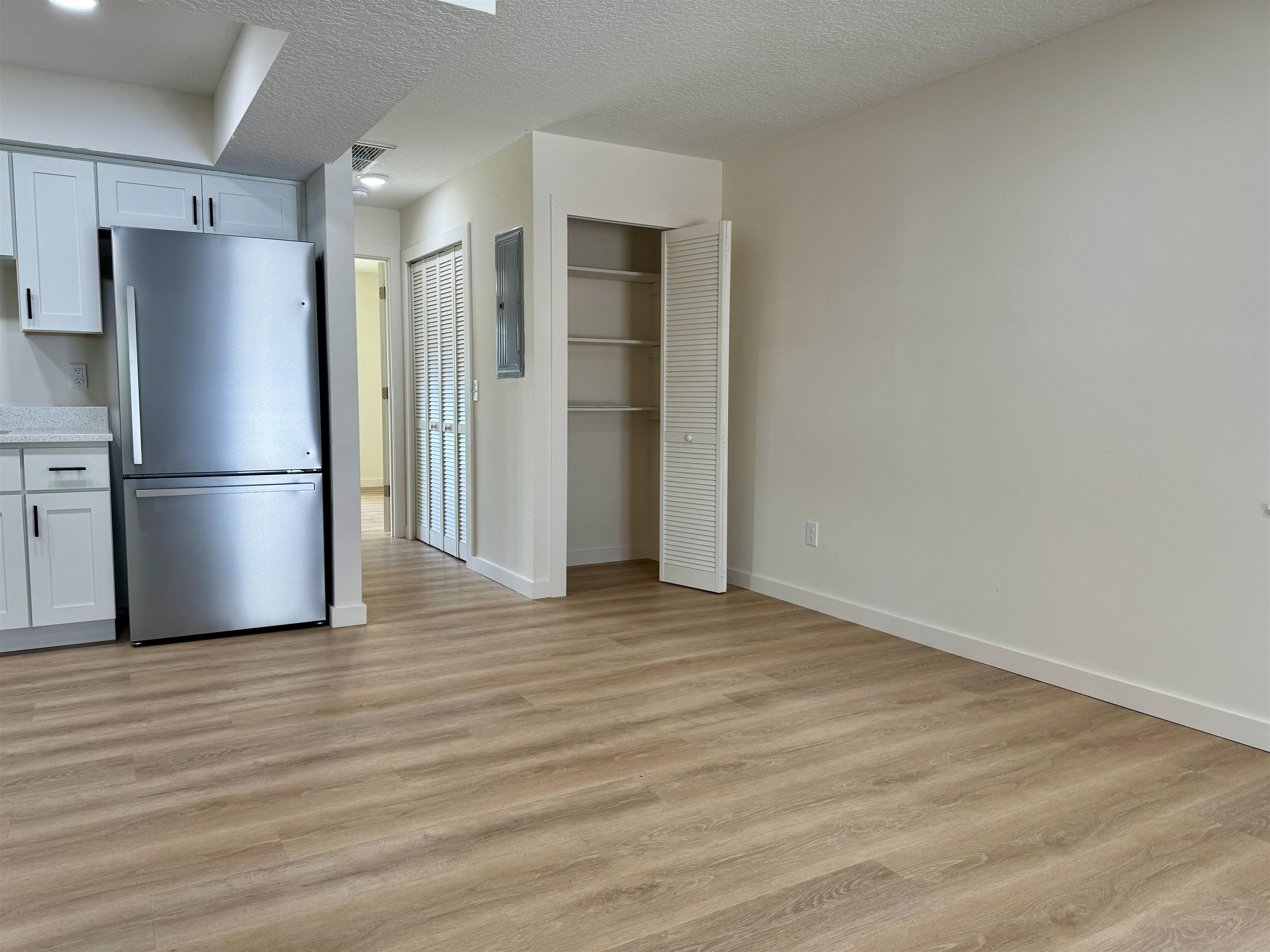 205 6th Street St. Augustine, FL 32080 - Photo 7 of 18 a view of an empty room with wooden floor and a refrigerator