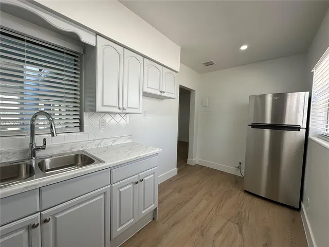 a kitchen with a refrigerator sink and cabinets
