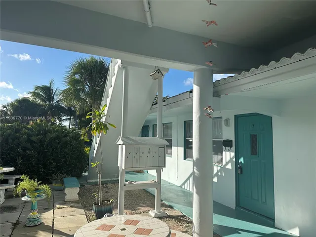 a view of a patio with table and chairs potted plants and palm tree