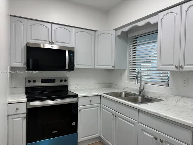 a kitchen with cabinets stainless steel appliances and a sink