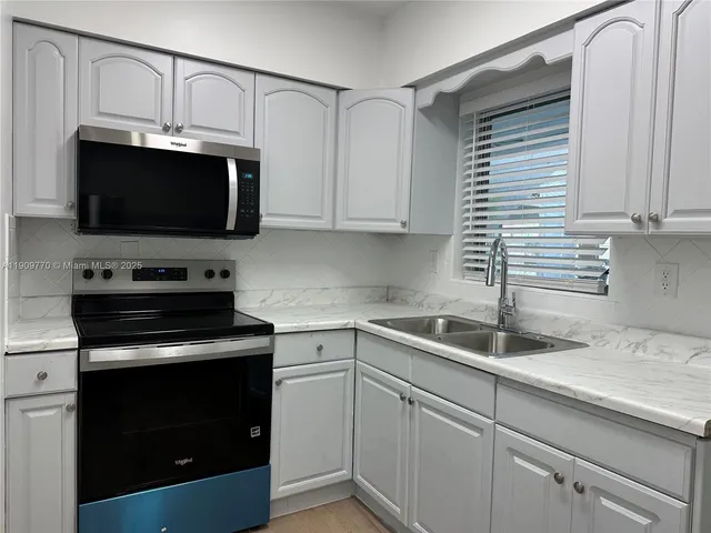 a kitchen with appliances a sink and cabinets