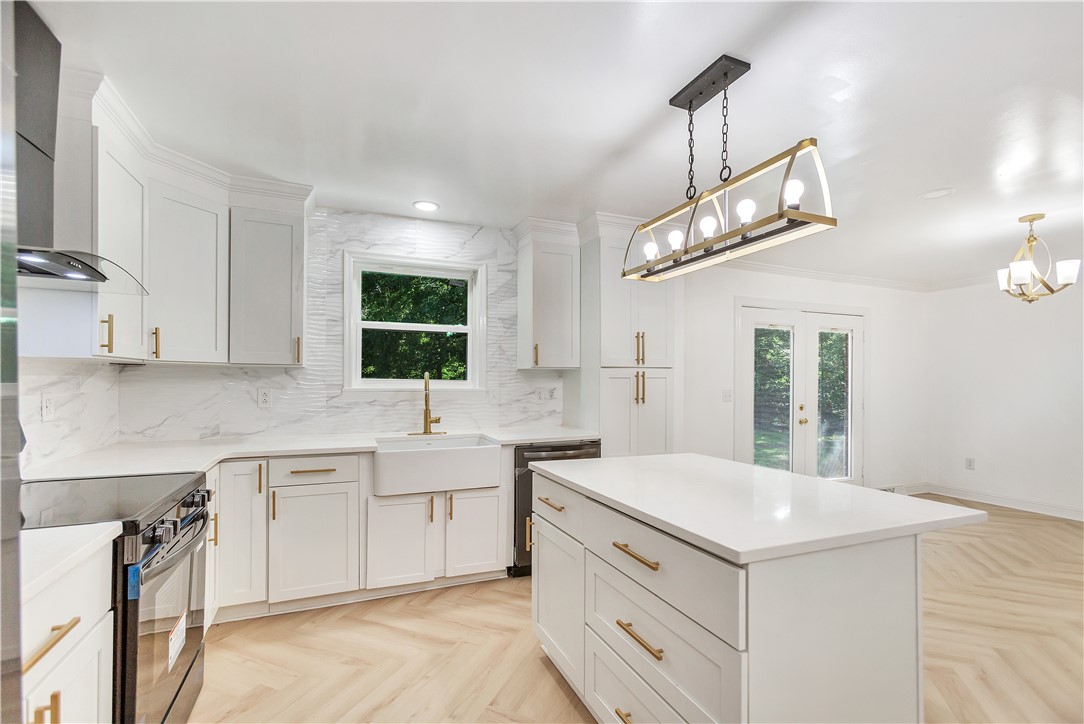 809 Paige Road Honea Path, SC 29654 - Photo 10 of 33 Modern kitchen featuring white shaker cabinetry, gold-finish hardware, a large kitchen island with countertop, stainless steel appliances, and herringbone pattern flooring