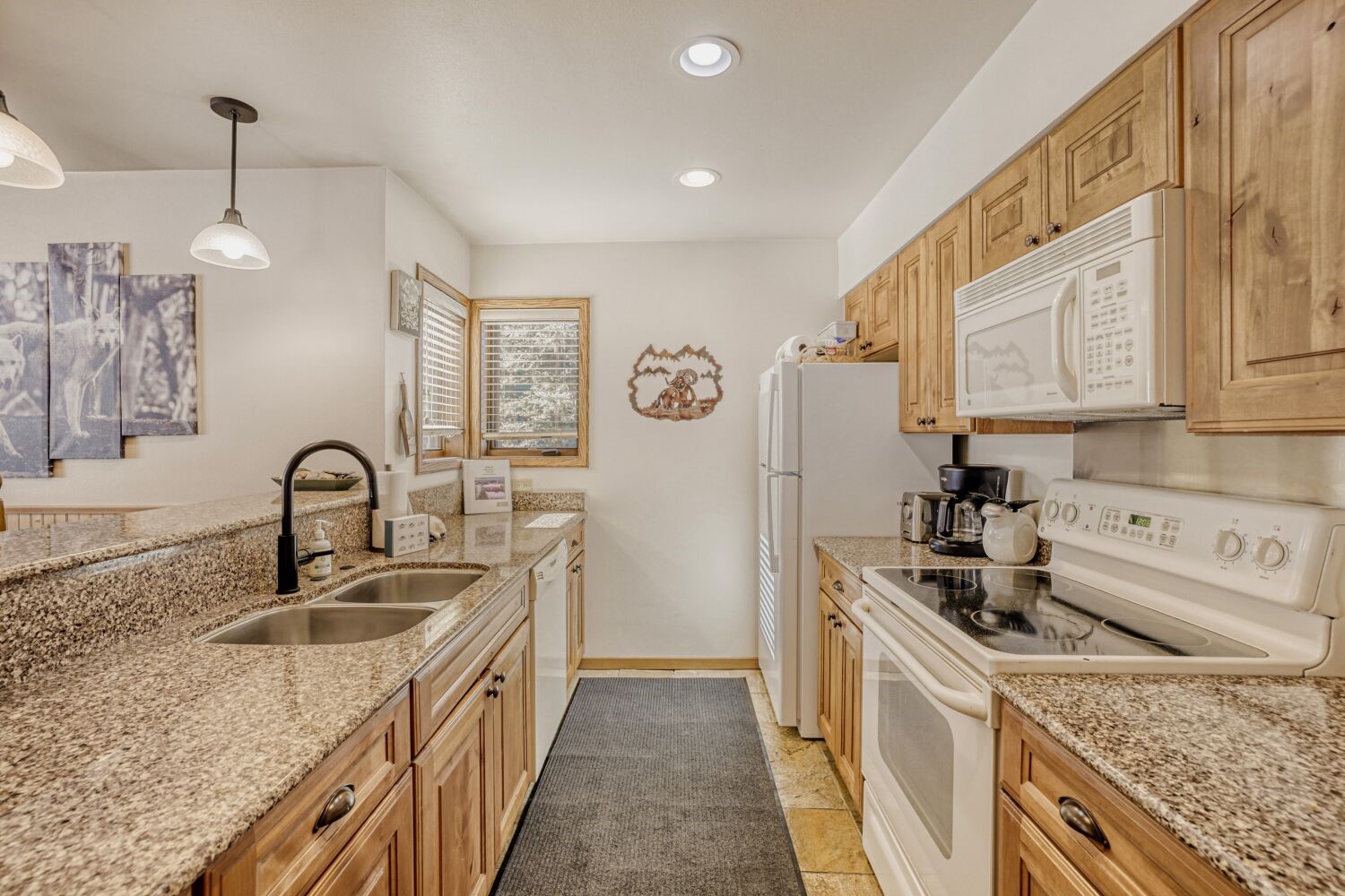 22804 Highway 6, Unit 108 Keystone, CO 80435 - Photo 23 of 28 Kitchen featuring white appliances, pendant lighting, light stone countertops, and light stone finish floors
