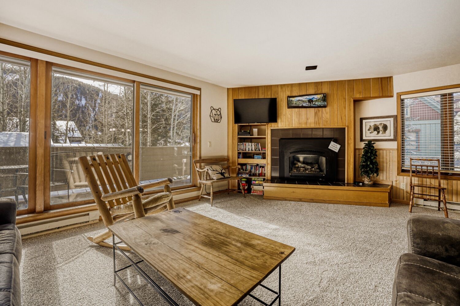 22804 Highway 6, Unit 108 Keystone, CO 80435 - Photo 4 of 28 Living area featuring light carpet, wooden walls, and a fireplace