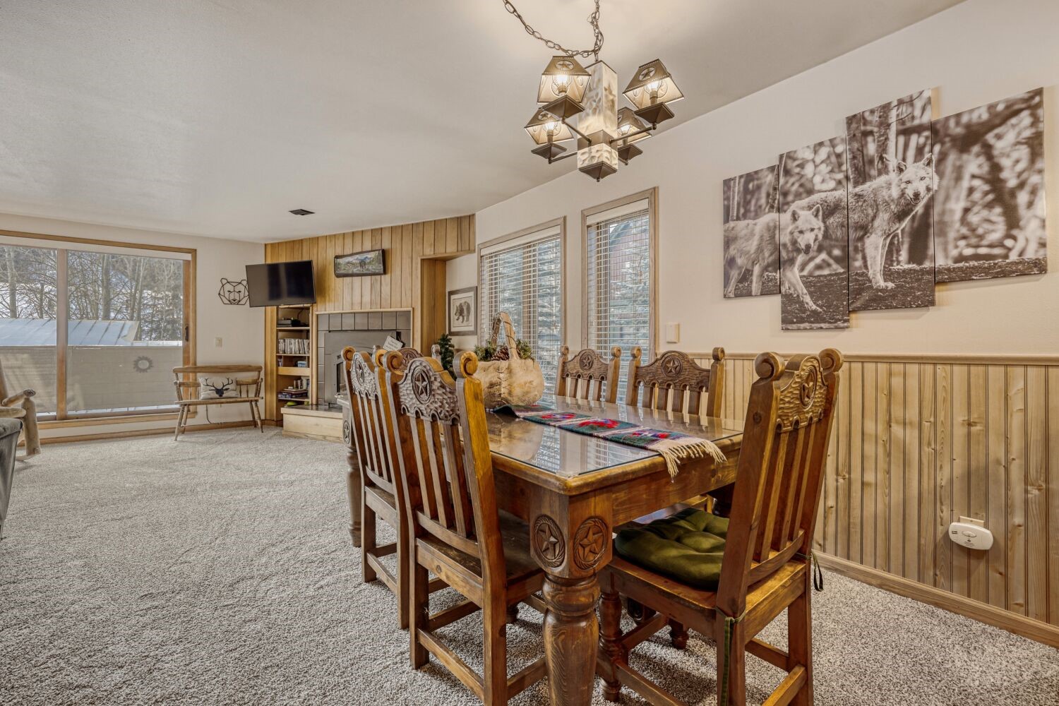 22804 Highway 6, Unit 108 Keystone, CO 80435 - Photo 6 of 28 Carpeted dining space with wooden walls, suspended lighting, healthy amount of natural light, a fireplace, and wainscoting