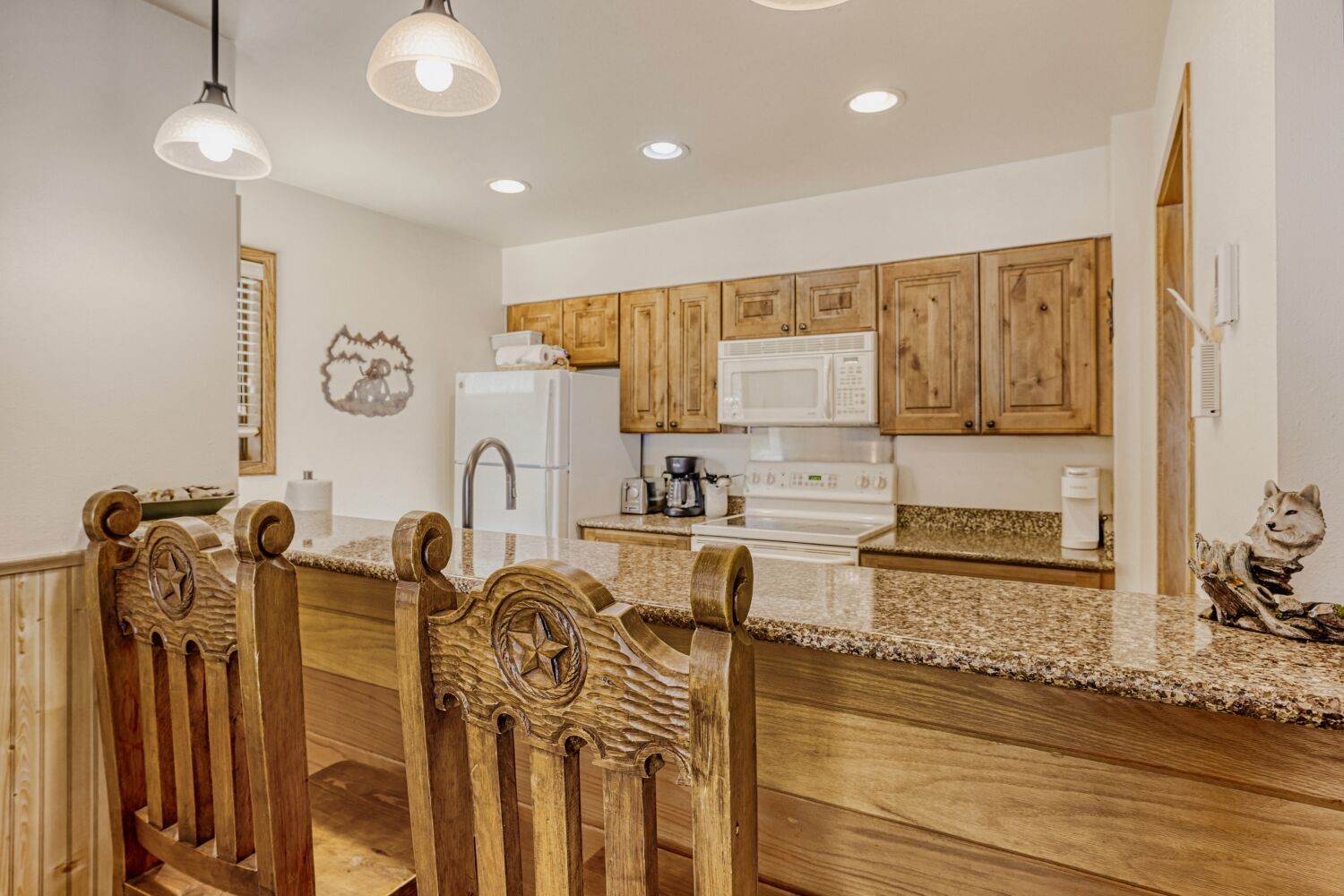 22804 Highway 6, Unit 108 Keystone, CO 80435 - Photo 7 of 28 Kitchen featuring light stone countertops, white appliances, decorative light fixtures, a peninsula, and a breakfast bar