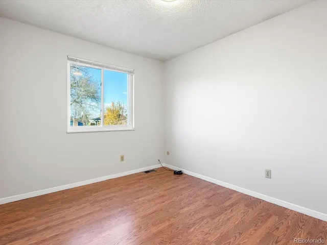 an empty room with wooden floor and window