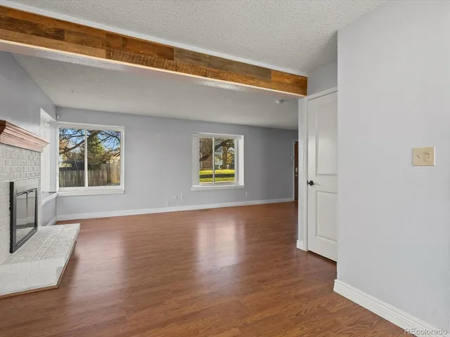 a view of an empty room with a window and wooden floor