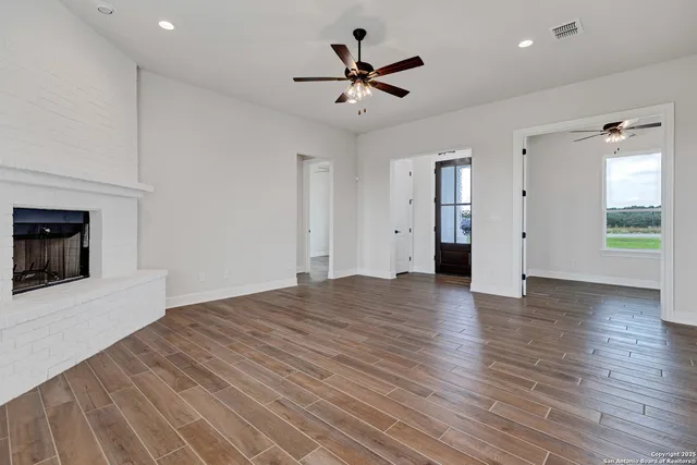 an empty room with wooden floor and a ceiling fan