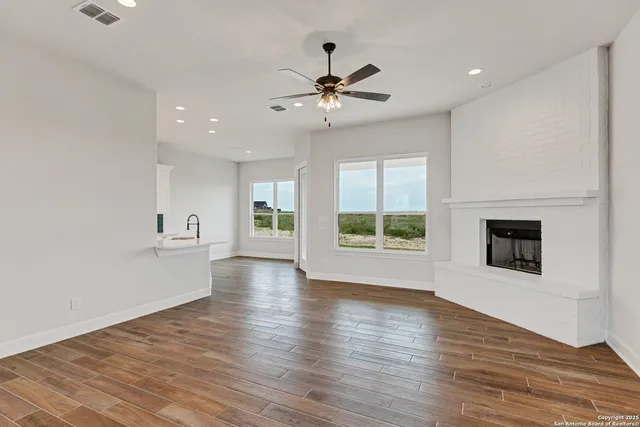 a view of an empty room with a window and wooden floor