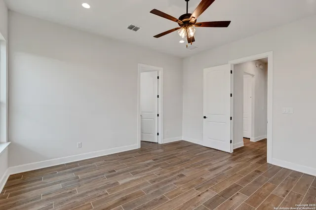 an empty room with wooden floor and a ceiling fan