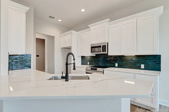 a kitchen with white cabinets and appliances