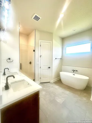 a spacious bathroom with a tub sink and mirror