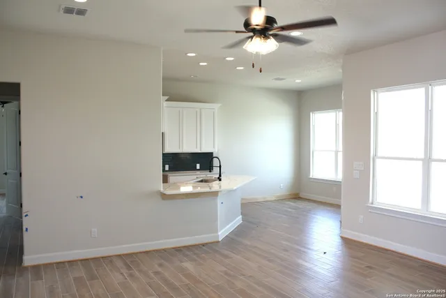 an empty room with wooden floor a ceiling fan and a window