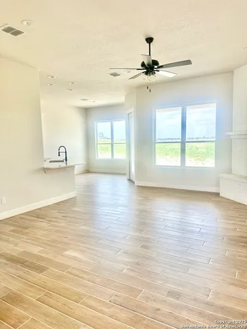 a view of an empty room with window and wooden floor