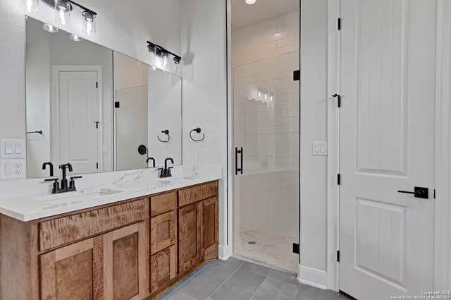 a bathroom with a double vanity sink and mirror with shower