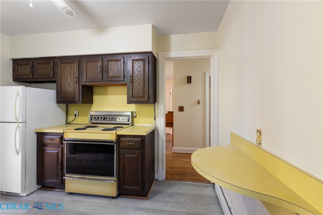275 Waverly Road Urbanna, VA 23175 - Photo 5 of 27 Kitchen featuring electric range oven, freestanding refrigerator, light wood-style flooring, dark brown cabinetry, and light countertops