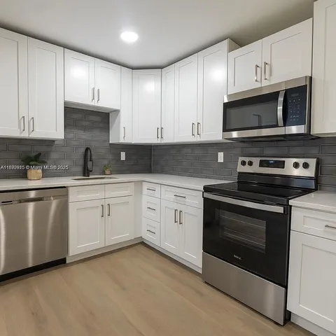 a kitchen with stainless steel appliances granite countertop grey cabinets a stove a sink and dishwasher