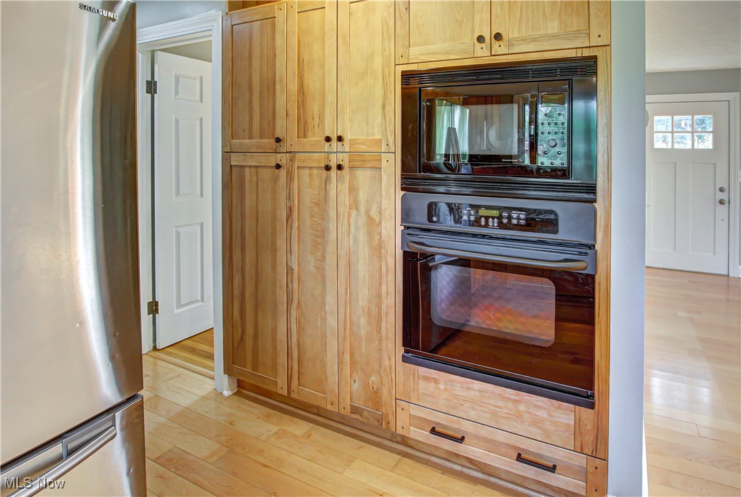 12477 Webster Road Strongsville, OH 44136 - Photo 11 of 40 Kitchen with black appliances, light brown cabinetry, and light hardwood / wood-style flooring