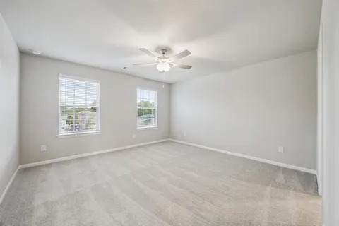 an empty room with windows and chandelier fan