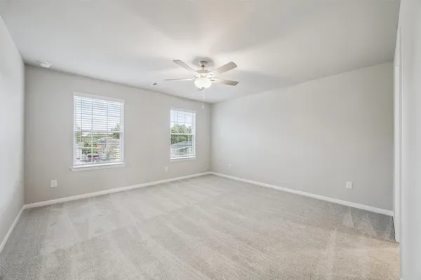 an empty room with windows and chandelier fan