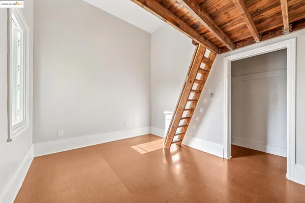a view of an empty room with wooden floor and stairs