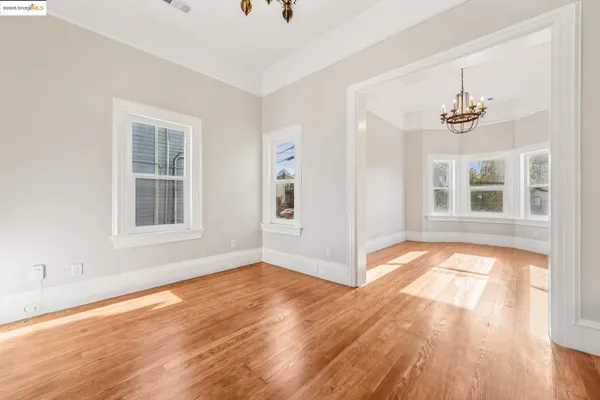 a view of an empty room with a window and wooden floor