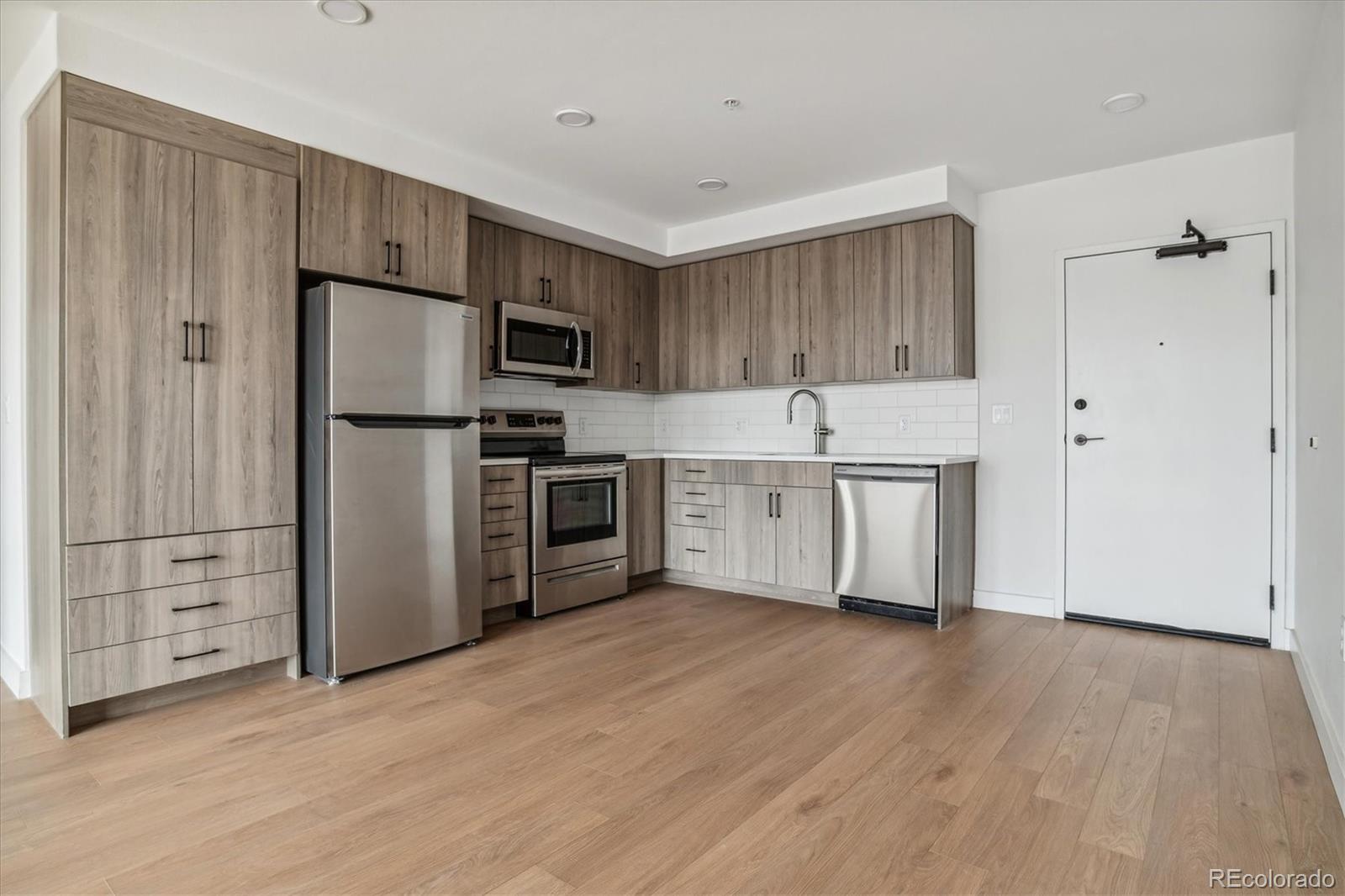 3575 Chestnut Place, Unit 702 Denver, CO 80216 - Photo 2 of 8 a kitchen with kitchen island a white cabinets and stainless steel appliances