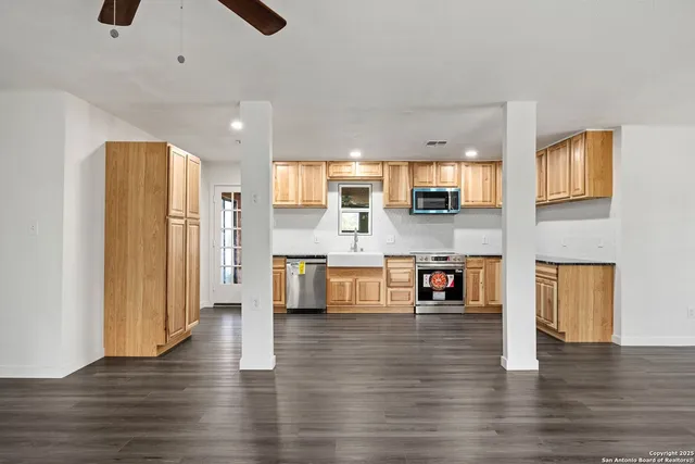 a large white kitchen with stainless steel appliances kitchen island a stove a refrigerator a oven and a large window