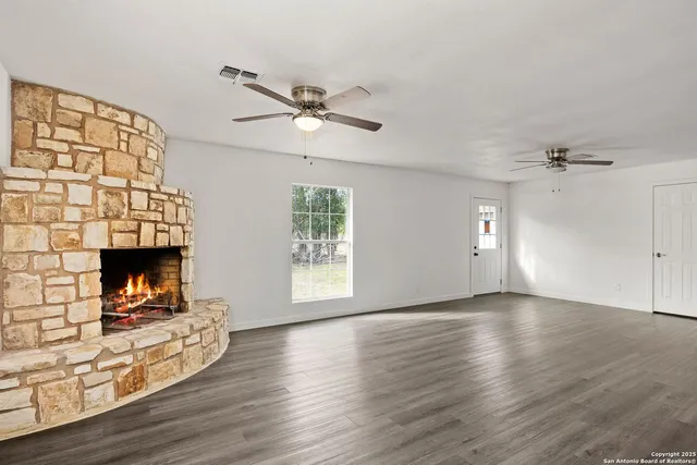 an empty room with windows fireplace and wooden floor