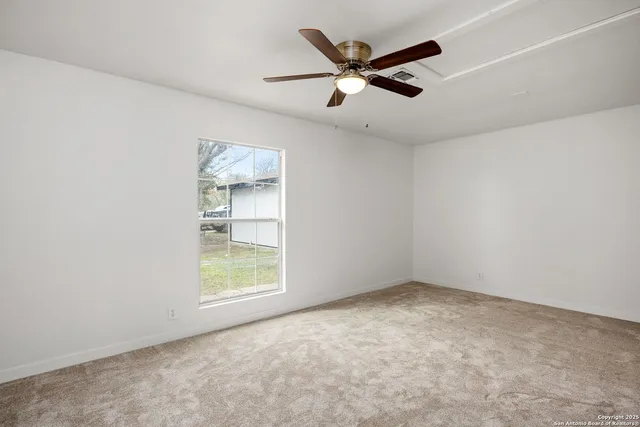 an empty room with a window and ceiling fan