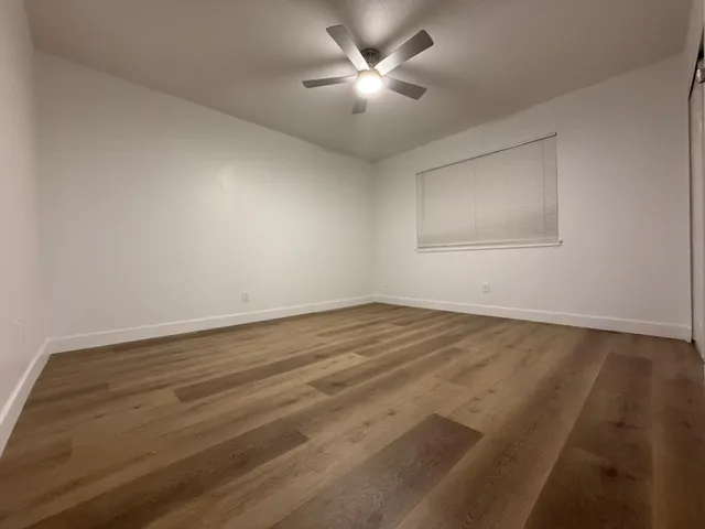 a view of a room with wooden floor and a ceiling fan