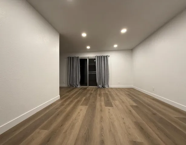 a view of an empty room with wooden floor
