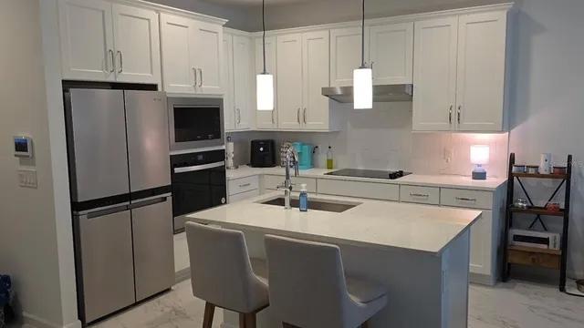 a kitchen with stainless steel appliances granite countertop a sink a refrigerator a stove a microwave and cabinets