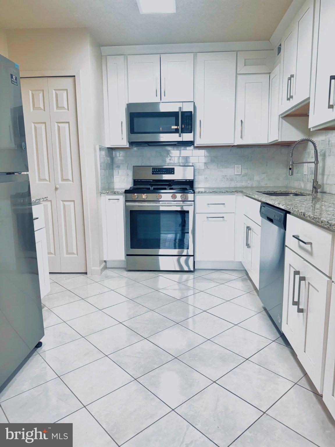 5225 Pooks Hill Road, Unit 1326 Bethesda, MD 20814 - Photo 4 of 24 a kitchen with granite countertop a stove a sink and a white cabinets