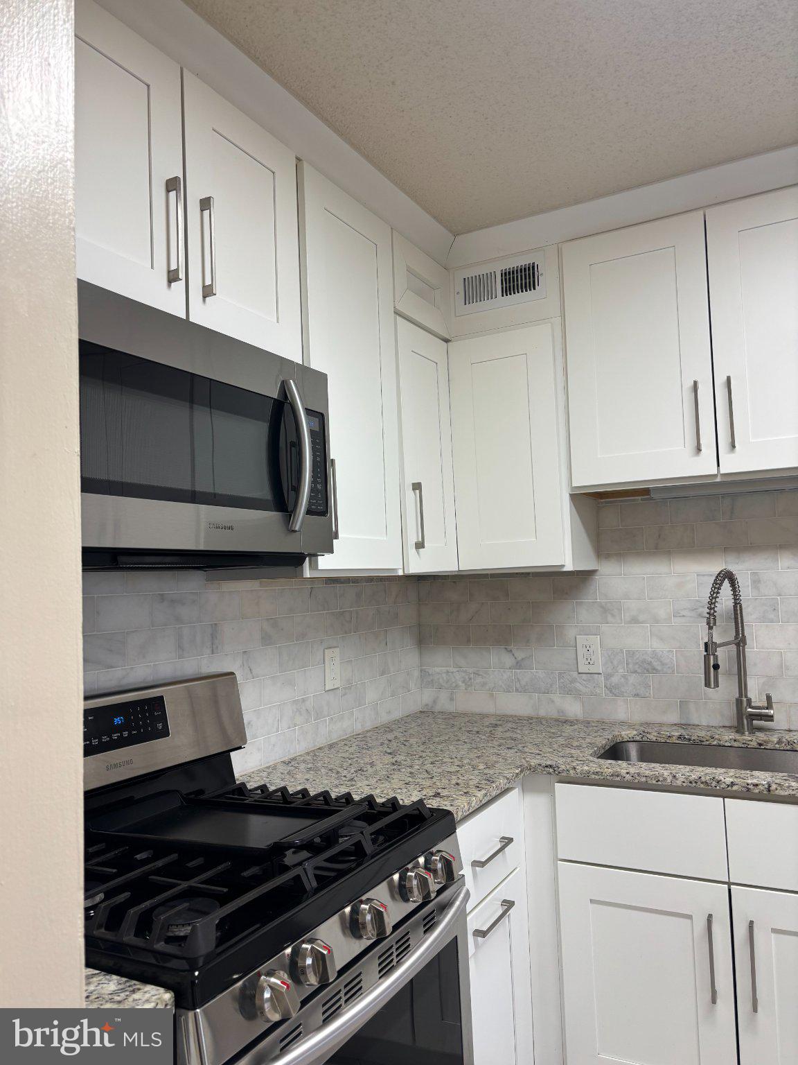 5225 Pooks Hill Road, Unit 1326 Bethesda, MD 20814 - Photo 5 of 24 a kitchen with stainless steel appliances granite countertop white cabinets and a stove top oven