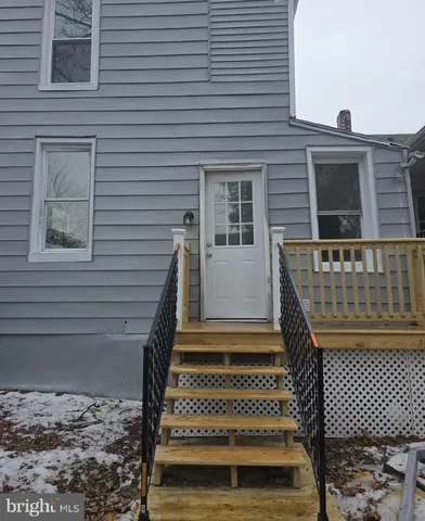 a view of house with wooden deck and furniture