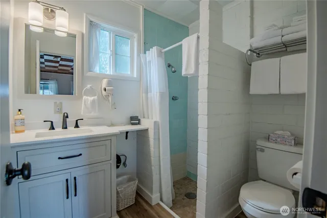 a bathroom with a sink a toilet a mirror and shower