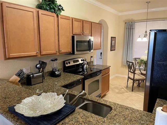 a kitchen with stainless steel appliances granite countertop a sink a stove and a refrigerator with wooden floor