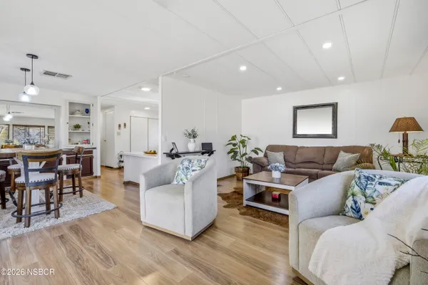 a living room with furniture a wooden floor and kitchen view